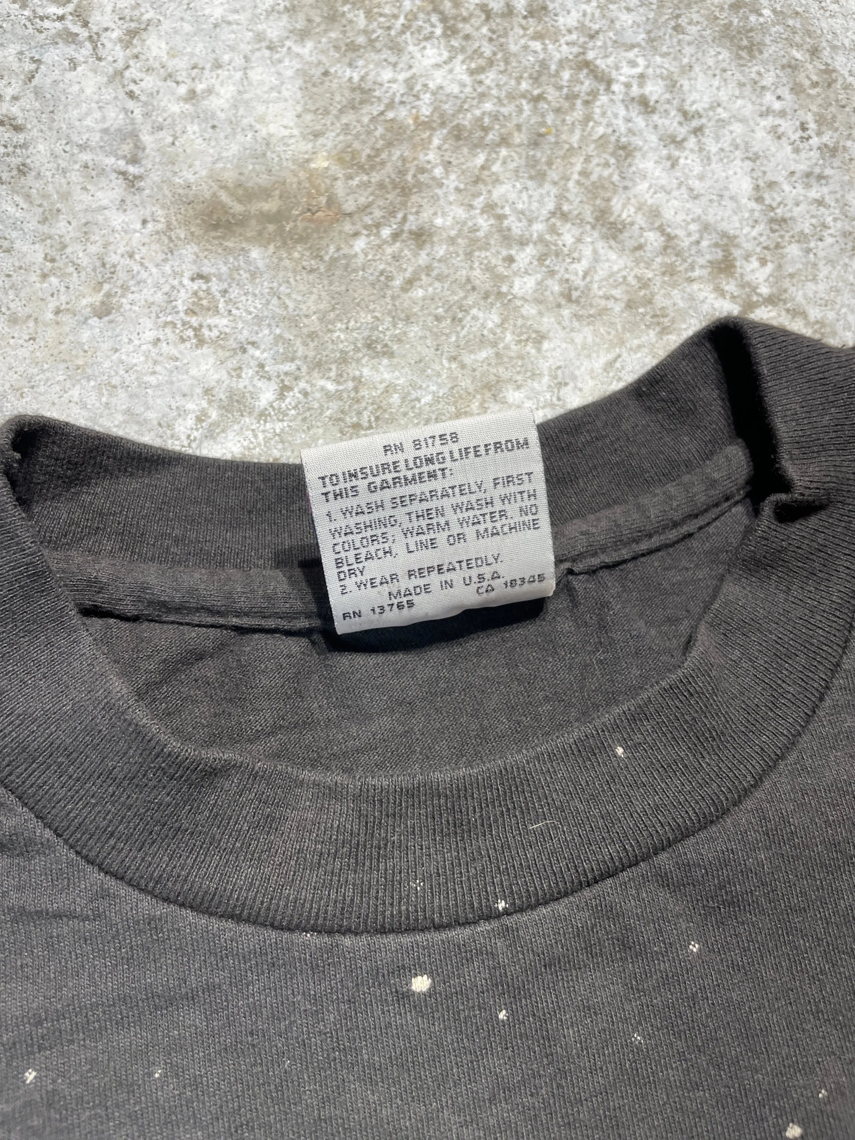 Vintage 1995 Grateful Dead black X-Large tee with faded fabric and white paint splatters, showing the care tag.